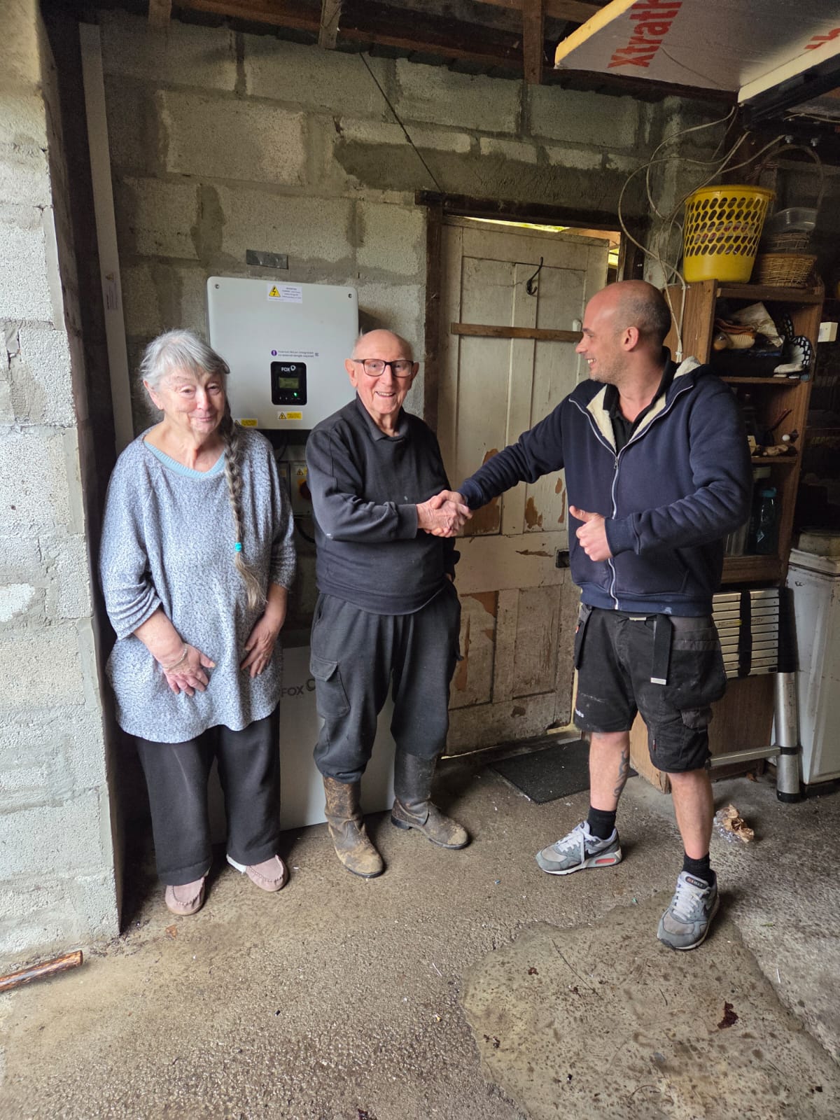 CCS engineer completing a FoxESS solar battery installation, handshake with happy customers